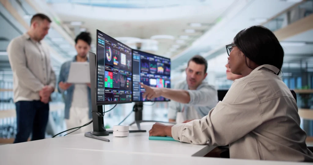 People sitting at a desk looking at two monitors